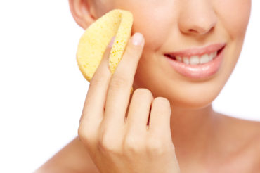 Fresh woman cleaning her face with sponge